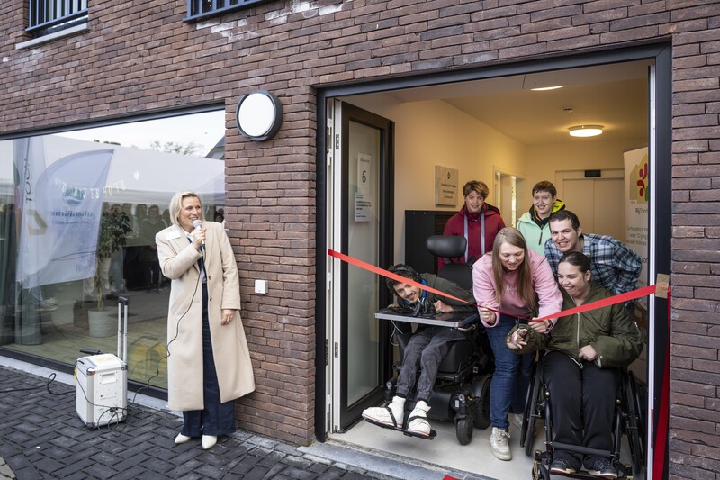 Enkele jongeren met een beperking knippen onder begeleiding een rood lint door dat aan de inkomdeur van het Toontjeshuis in Sint-Niklaas gespannen werd.