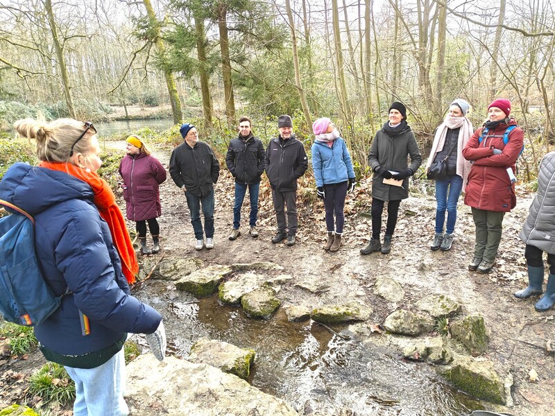 In een bos lopen enkele mensen op een wandelpad bedekt met houtschors.