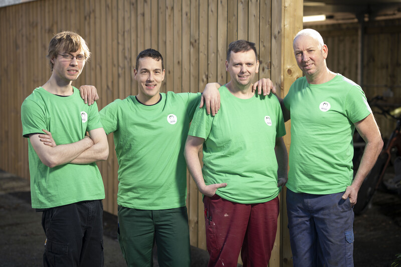 Vier ACV-afgevaardigden bij OMCO Metals in Hamme poseren met een groene t-shirt aan.