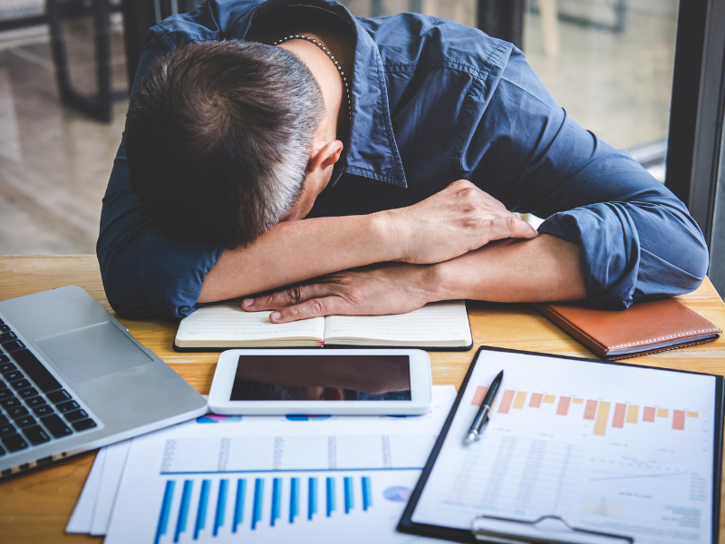 Man heeft hoofd op tafel van vermoeidheid en werkstress