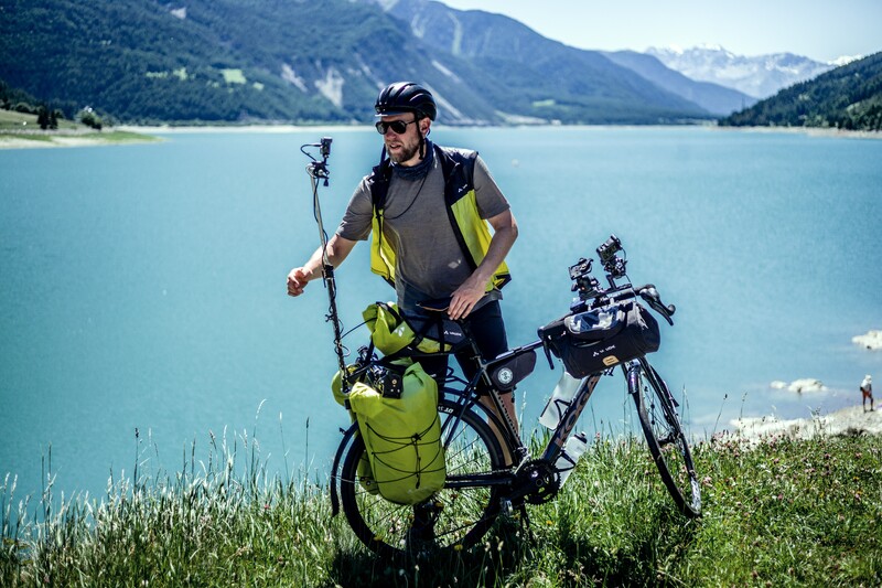Wouter Deboot staat met fiets en opnameapparatuur aan een meer