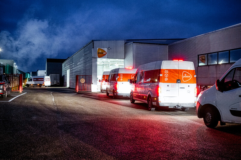 Rij wachtende bestelwagens voor de poort van het verdeelcentrum van PostNL in Sint-Truiden