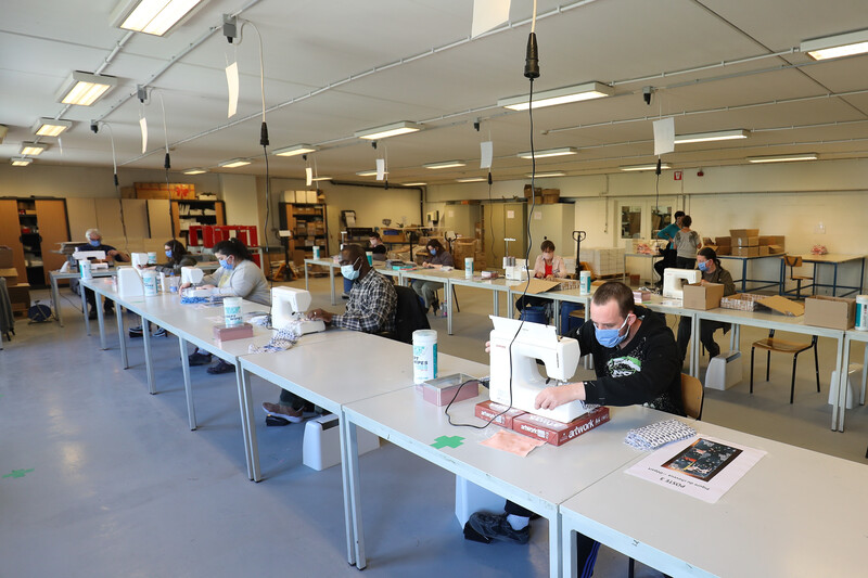 Werknemers met mondmasker in maatbedrijf aan het werk