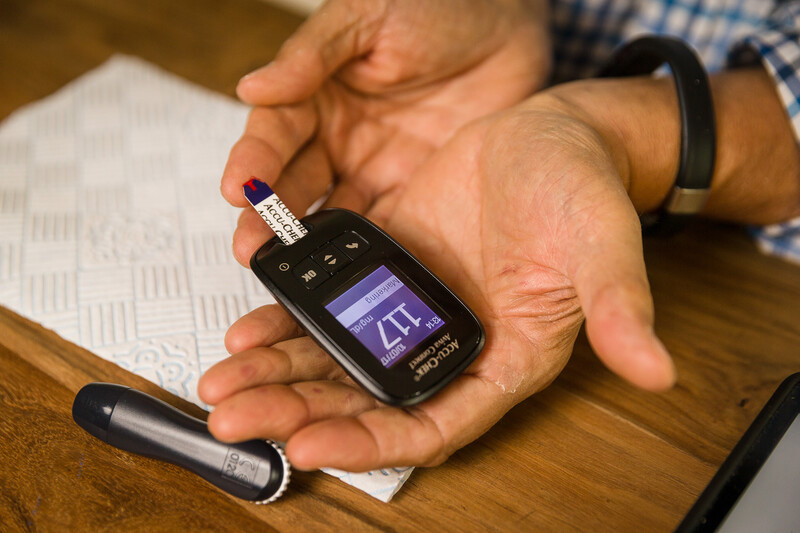 Man prikt bloed om waardes in bloed te meten met toestel