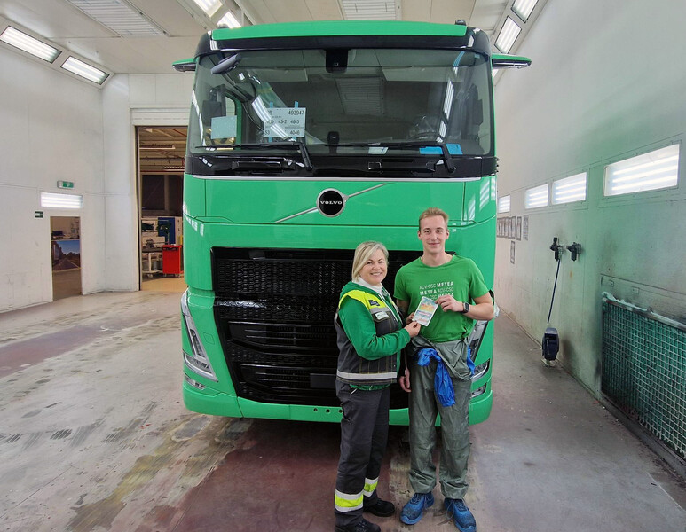Twee werknemers van Volvo poseren met een flyer voor een groene vrachtwagen.