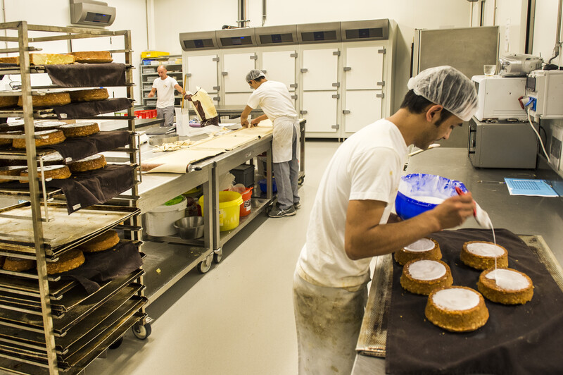 Bakkerij met medewerker die glazuur op taarten smeert
