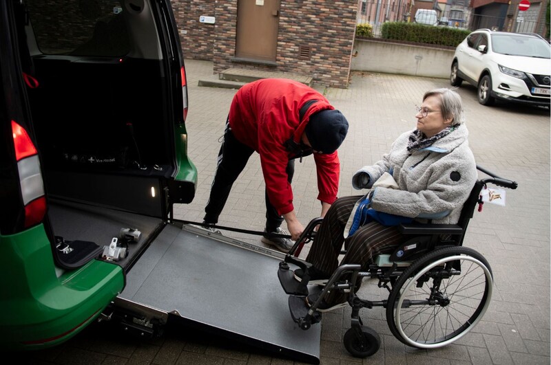 man helpt rolstoelgebruiker in speciaal aangepast busje