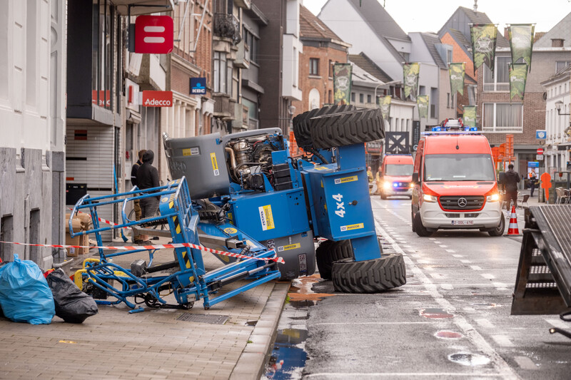 zicht op een winkelstraat met omgevallen hoogtewerker, brandweer op achtergrond