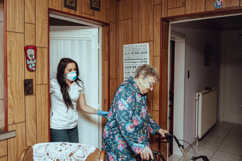 thuisverpleegster helpt oudere vrouw met rolator