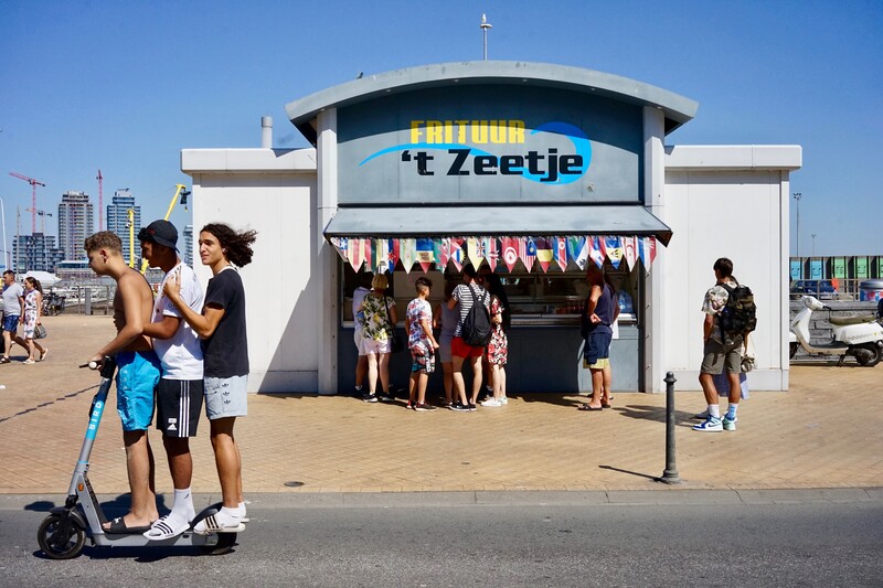 Kinderen op elektrische Bird step voor Frituur 't Zeetje aan de Belgische kust
