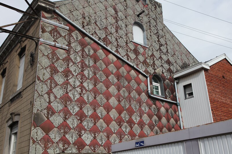 Verweerde gevel van huis met asbestbekleding