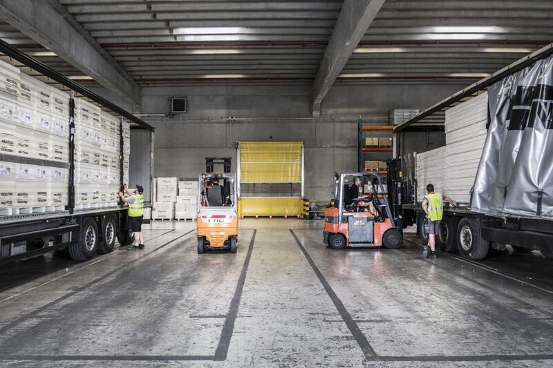 Werknemers zijn aan het werk met heftrucks in een magazijn.
