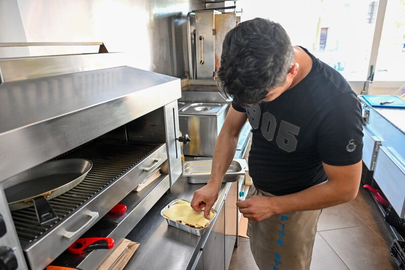 Een man in een snackbar maakt het gerecht kapsalon klaar