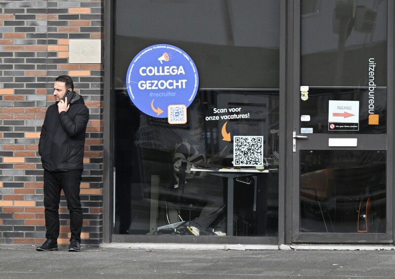 Man bellend voor de vitrine van een uitzendkantoor