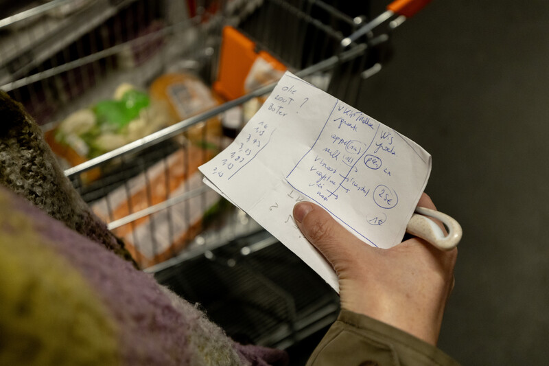 Vrouw met boodschappenlijst in hand in Colruyt supermarkt