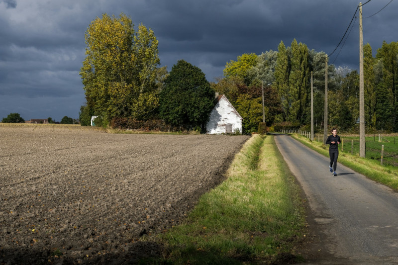 Loper door droge akkers tijdens dreigende onweersbui.