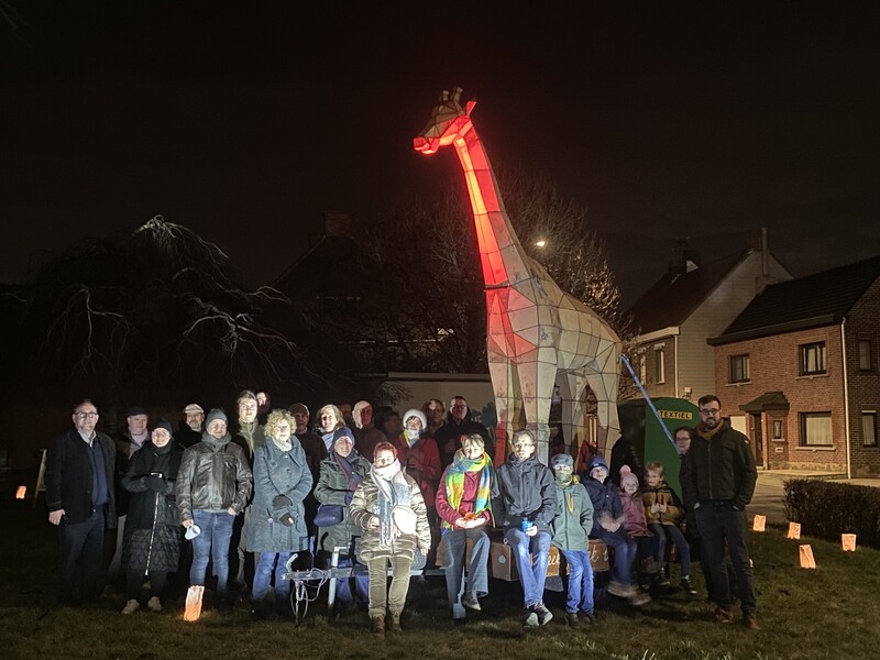 Een 25-tal buurtbewoners poseren bij een levensgrote houten giraf.