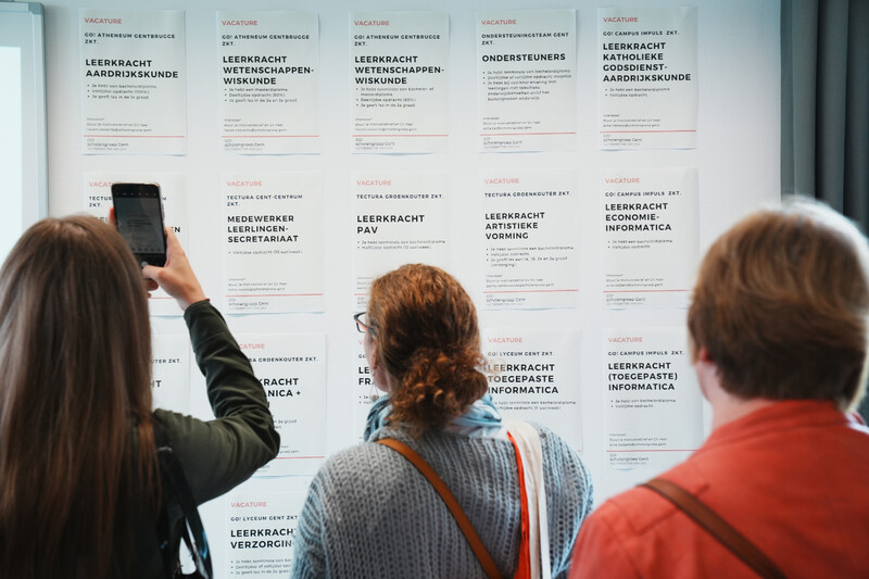 Mensen bekijken een muur vol vacatures in het onderwijs