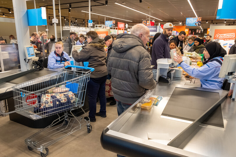 Vrouw met hoofddoek werkt achter kassa supermarkt Albert Heijn