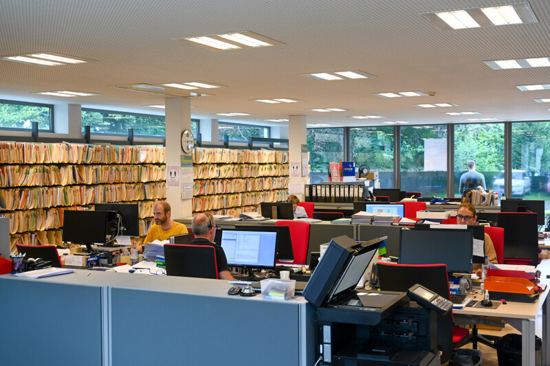 kantoor met bedienden achter computer naast grote dossierkast