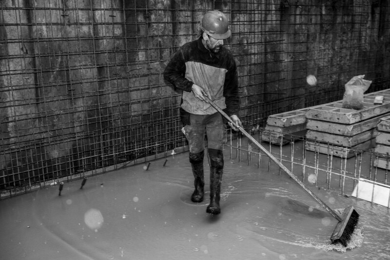 Bouwvakker veegt water weg op een werf