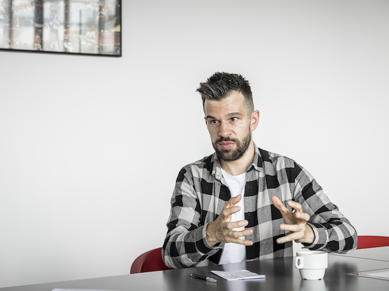 Stijn Baert in ruitjeshemd aan een tafel, met handen gesticulerend