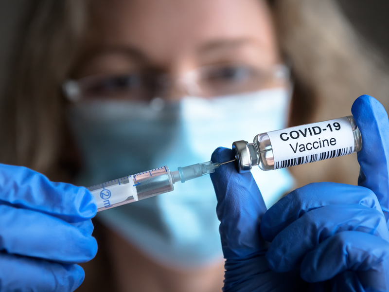 Vrouw trekt dosis vaccin uit flacon