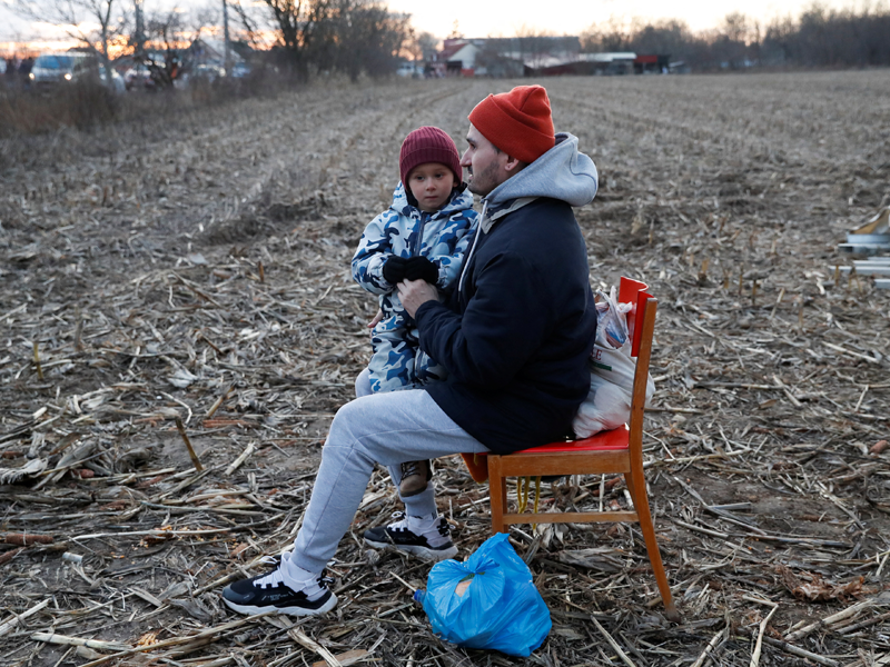 Man zit samen met zoon op stoel te wachten in Oekraïense droge weide