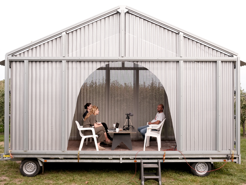 Man en vrouw bevragen man in een schuur op wieltjes