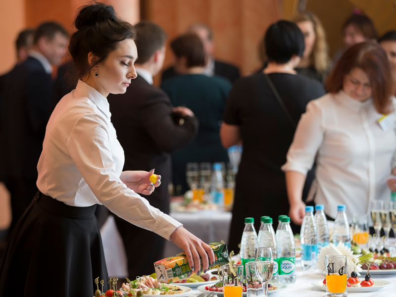 Serveerster schenkt glazen fruitsap bij op receptie