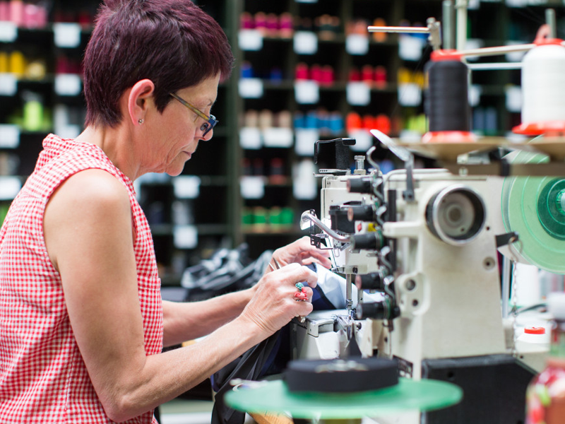 Oudere vrouw die werkt aan een naaimachine