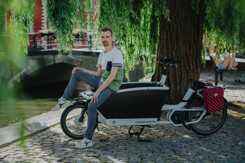 Professor Wim Van Lancker op bakfiets onder boom.