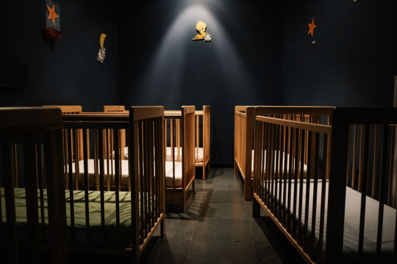 Drie lege babybedjes staan in een donkere kamer