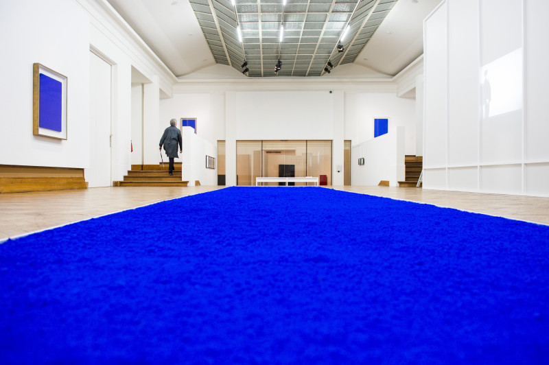 Museumzaal met blauw tapijt en blauwe schilderijen
