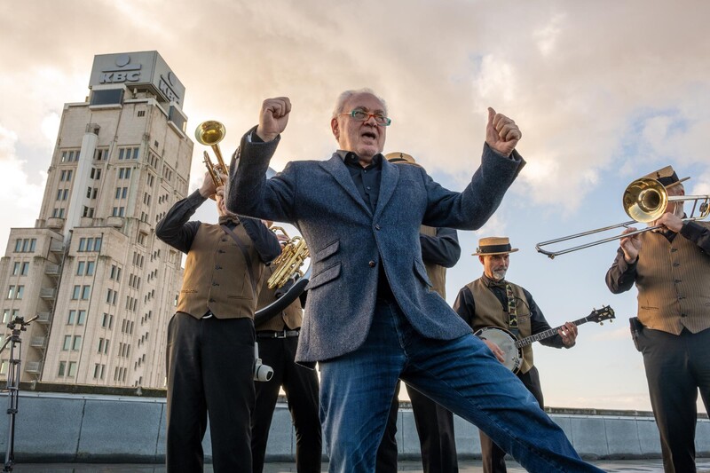 Fernand Huts dansend met orkest en Boerentoren in Antwerpen op achtergrond