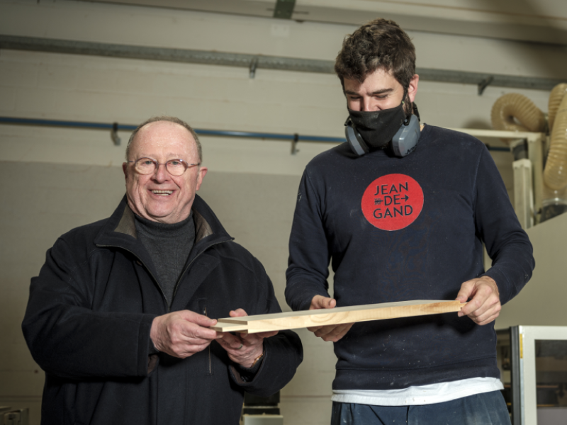 Luc Cortebeeck houdt samen met arbeider een houten plank vast