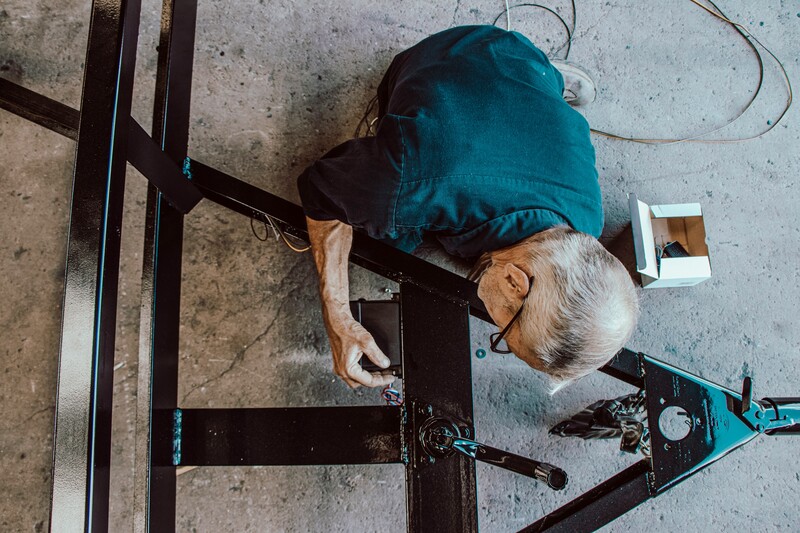 Oudere man werkt aan metalen frame