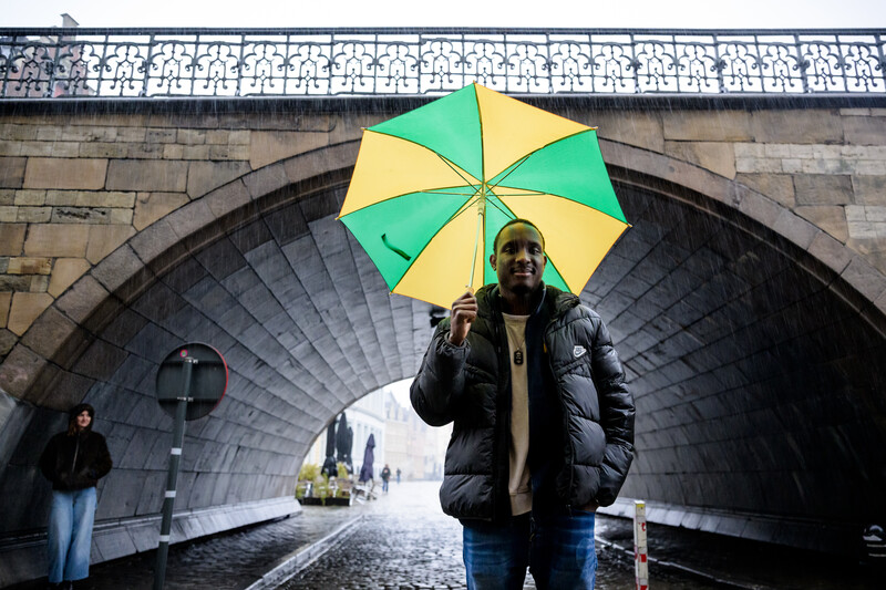 Siméon Severino met kleurrijke paraplu onder een brug in Gent