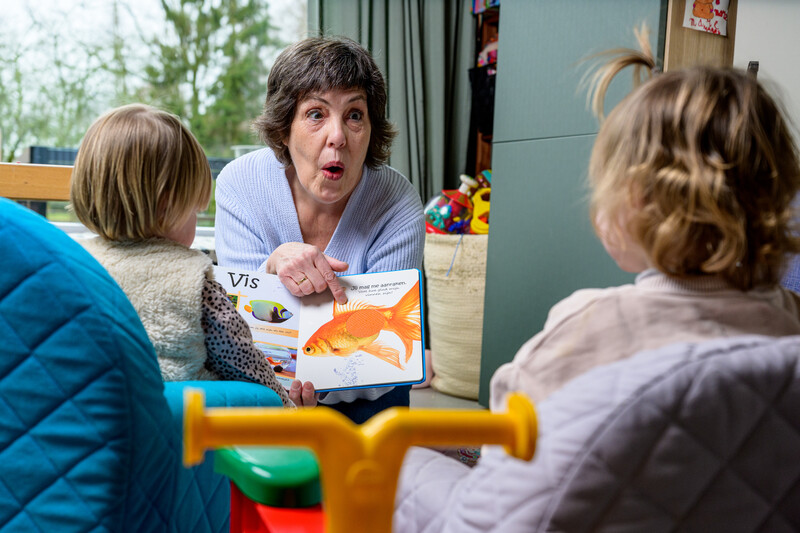 Onthaalmoeder leest boek voor aan twee kleuters