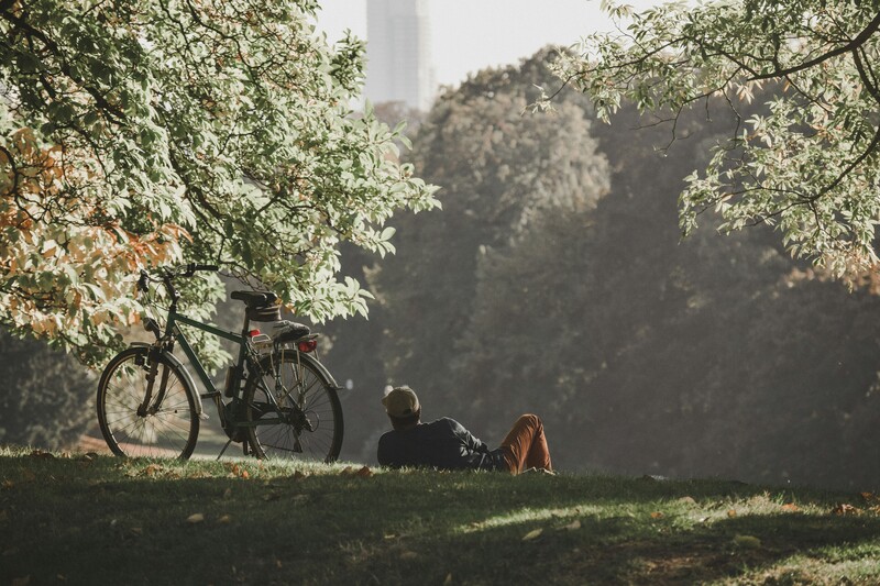 Man geniet van zon in park naast zijn fiets