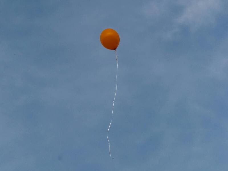 Een rode ballon waait omhoog in de lucht