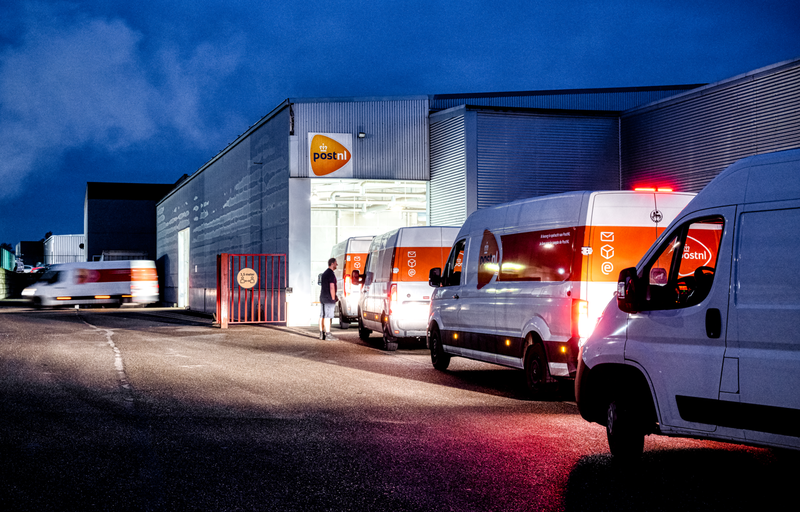 Busjes van PostNL staan in de vroege ochtend aan te schuiven voor lading.