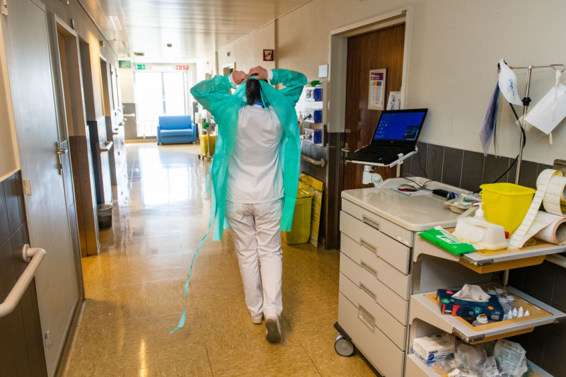 Verpleegkundige die schort aantrekt in gang UZ Gent