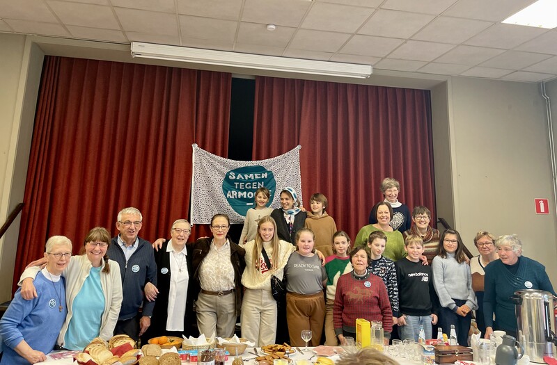 Jong en oud staan schouder aan schouder bij een ontbijtbuffet om de boodschap 'Samen tegen armoede' kracht bij te zetten.