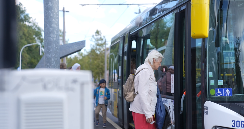 Een vrouw stapt op de bus aan de halte.