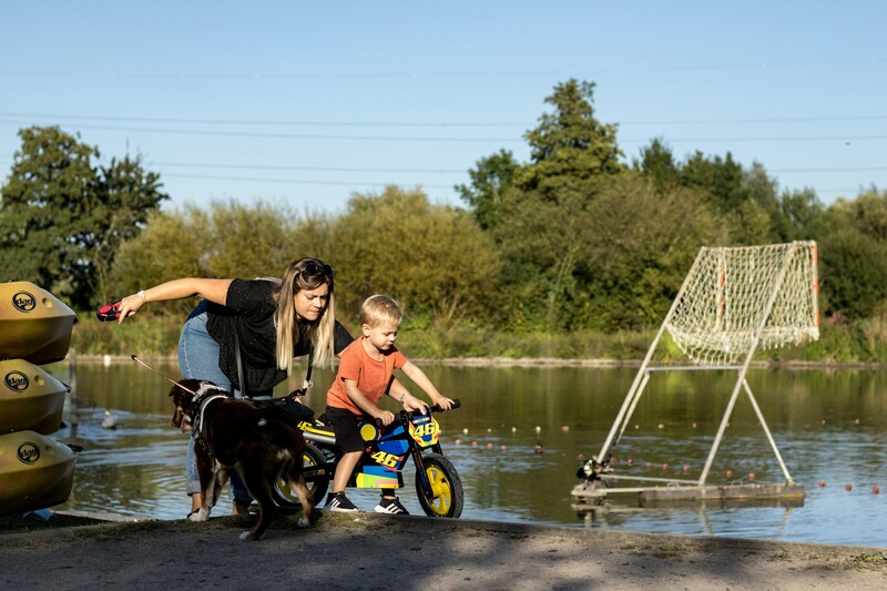 Vrouw met fietsen kind aan waterkant