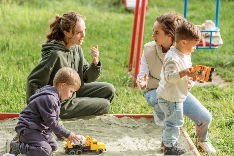 twee vrouwen met kinderen in de zandbak