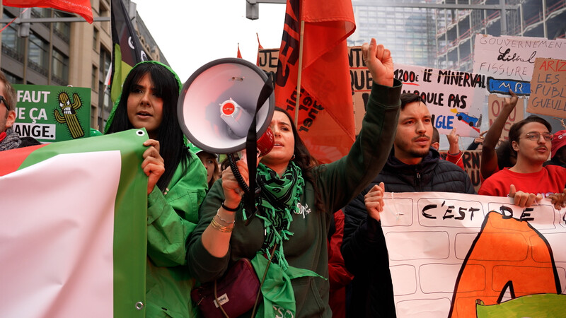 vrouw met megafoon en betogers met spandoeken