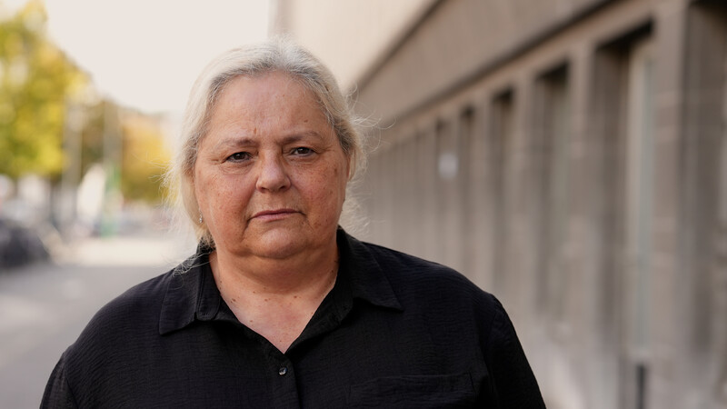 vrouw met grijze haar buiten naast grijze muur