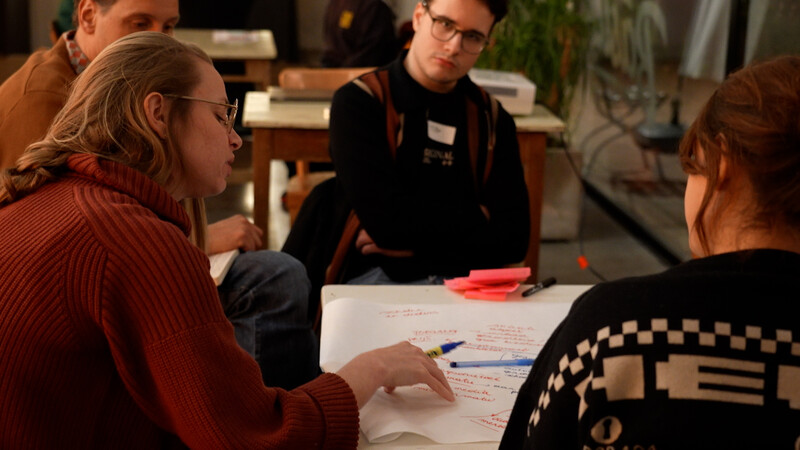Studenten brainstormen aan tafel en schrijven ideeën op